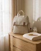 Sac à dos à langer rayé beige posé dans une chambre de bébé